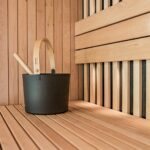 a wooden sauna with a black bucket and two wooden spoons