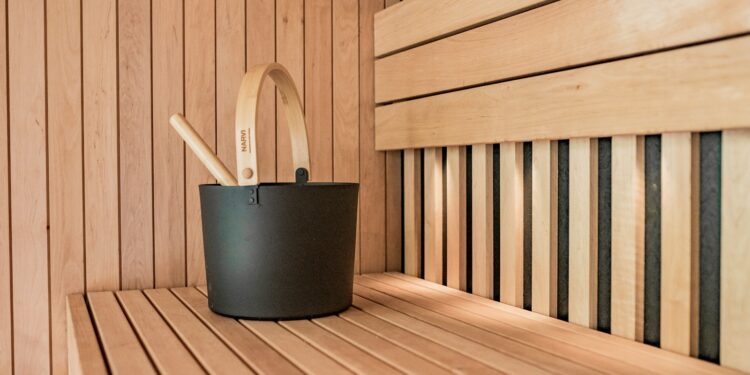 a wooden sauna with a black bucket and two wooden spoons